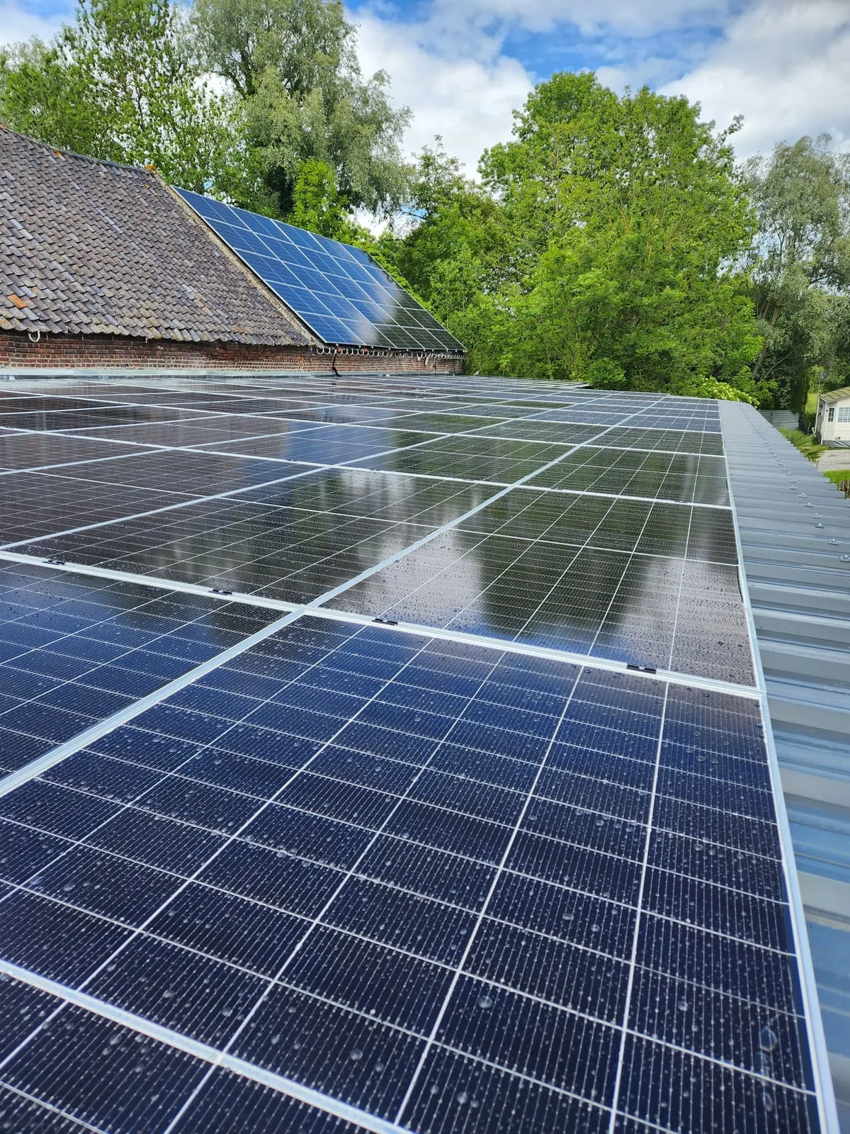 Grande toiture couverte de panneaux photovoltaïques, sous la pluie.