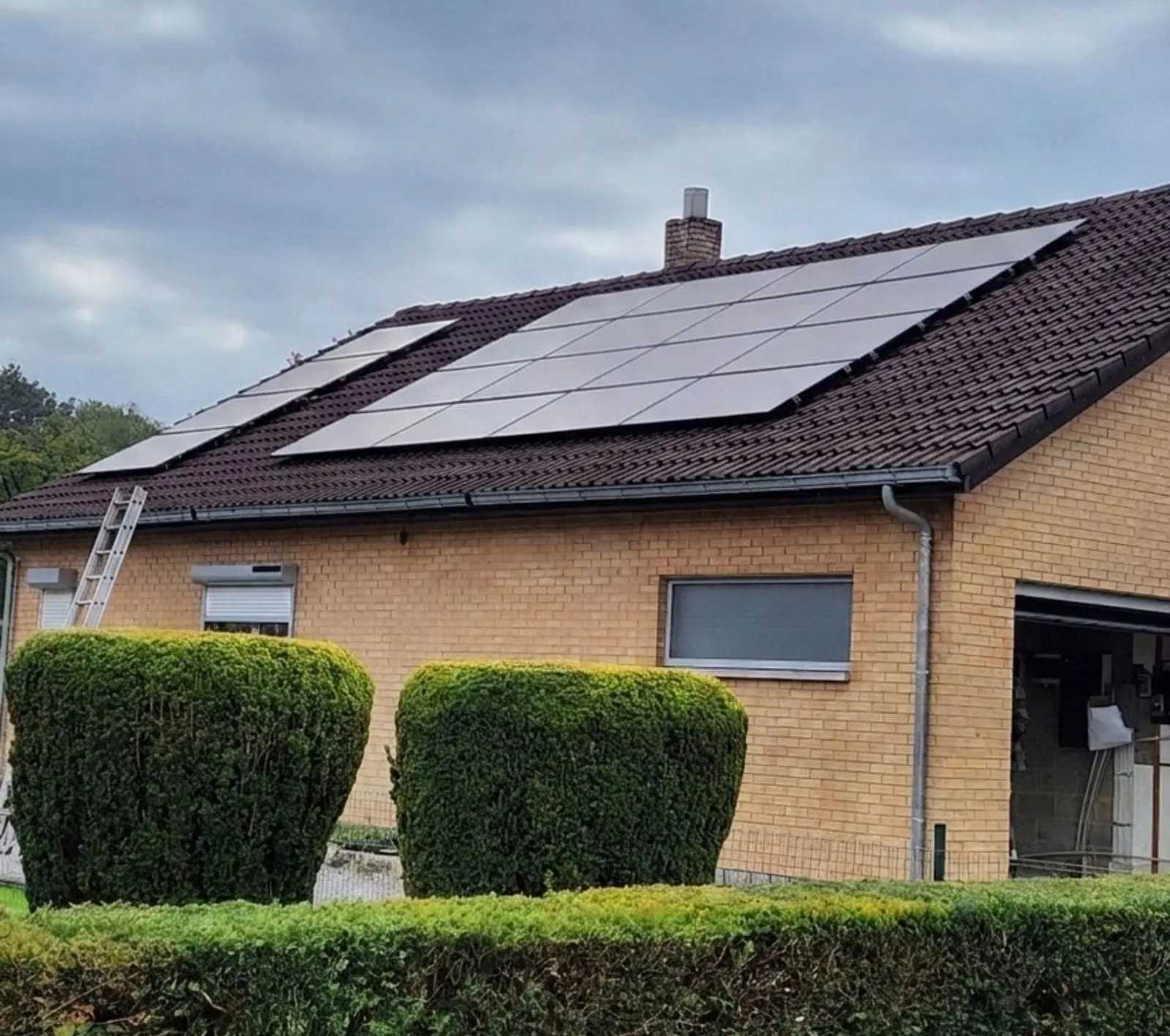 Maison avec toiture en tuiles sombres couverte de panneaux photovoltaïques.